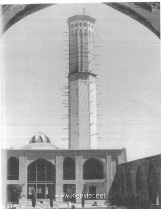 Hình 1: HỆ THỐNG LÀM MÁT TỰ ĐỘNG làm mát toà nhà ở thành phố Yazd, Iran: tháp đo gió, mái vòm và lỗ thông hơi. Tháp đo gió có tác dụng làm mát không khí bên ngoài và lưu thông gió trong toà nhà. (Hai đầu của xà gỗ dùng để gia cố công trình nhô ra khỏi toà tháp, hai đầu được đặt ở đó tạo giá đỡ cho giàn giáo để bảo quản toà tháp.) Mái vòm ở bên trái toà tháp có tác dụng giữ cho căn phòng dưới mái luôn mát mẻ. Kết cấu hẹp trên nóc mái vòm bao phủ lỗ thông hơi có vai trò giữ căn phòng phía dưới luôn luôn mát mẻ và duy trì sự lưu thông không khí trong ngôi nhà. Ba hệ thống giữ cho toà nhà dễ chịu trong suốt những tháng mùa hè.